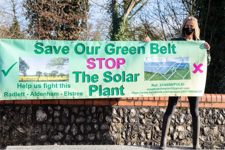 Sharon Woolf pictured in Radlett with an anti-solar farm banner. Credit: Lynn Margolis Photography