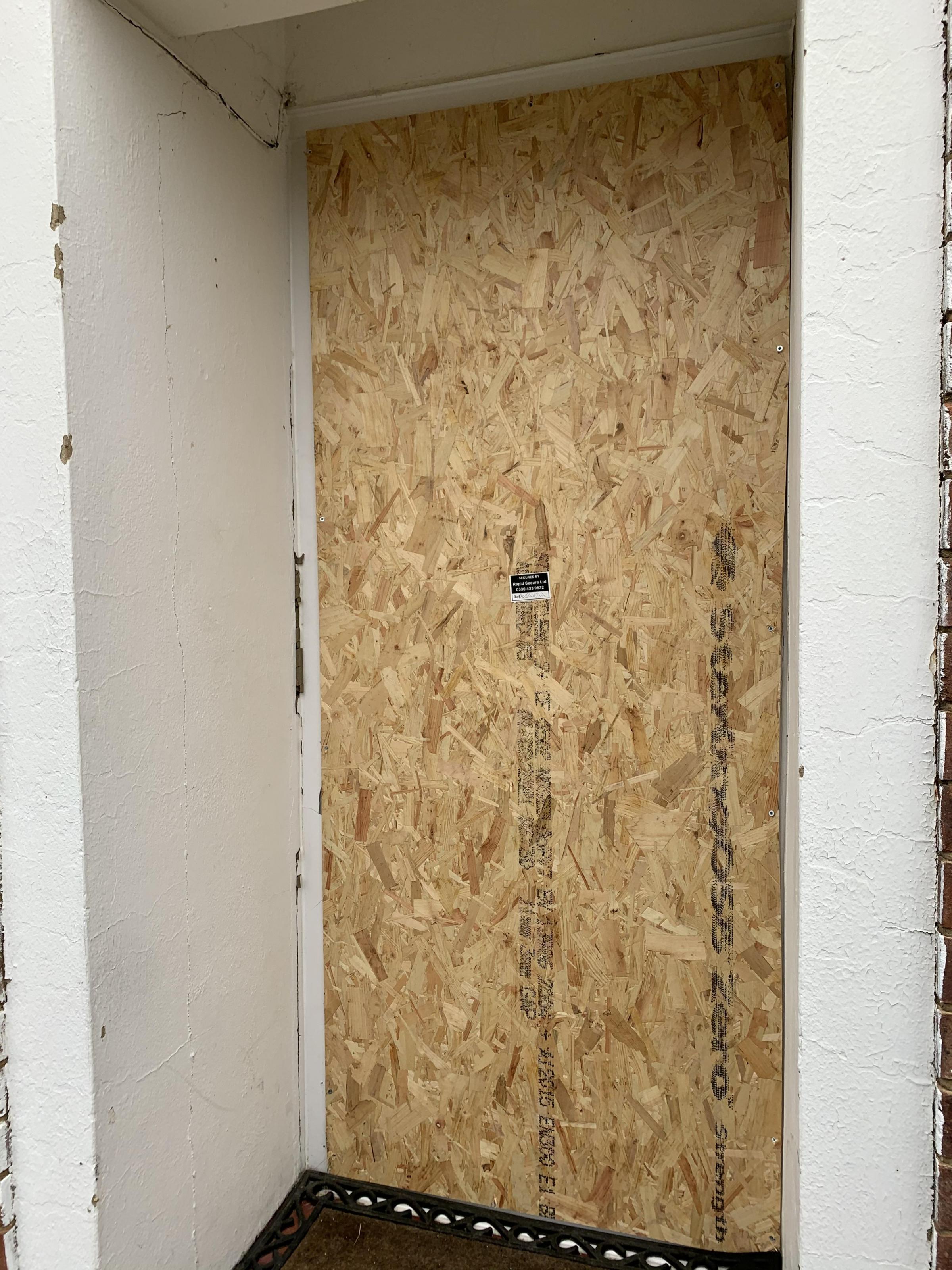 The boarded up door after the raid