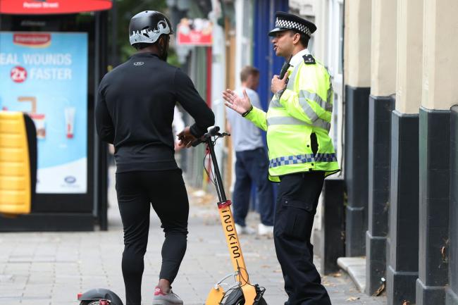 A police officer speaks to a private e-scooter rider