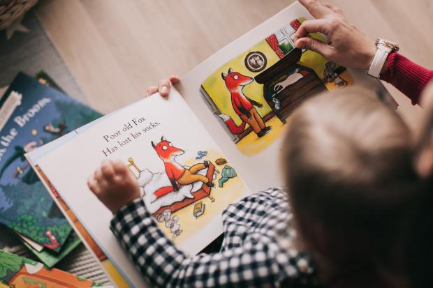 Borehamwood Times: A child reading a picture book with their parent. Credit: Canva